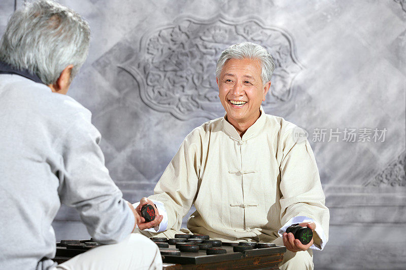 two oriental senior adults play chinese chess